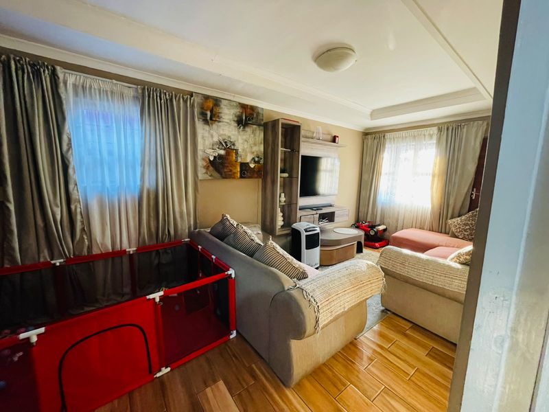 A comfortable living room featuring tiled flooring, a recessed ceiling, and a built-in media unit, offering a functional space for relaxation.