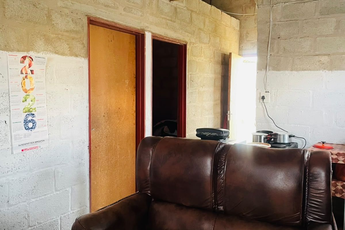 A living area featuring exposed concrete block walls and timber roof trusses, currently in an unfinished state requiring ceiling and wall completion.