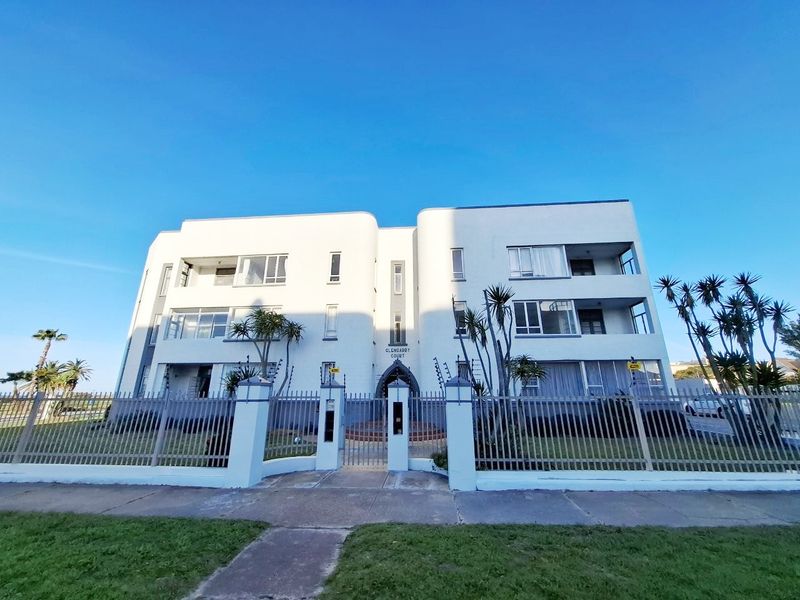 Front elevation of Glencarry Court apartment building featuring a secure gated entrance, perimeter fencing, and multi-level balconies under a clear blue sky.