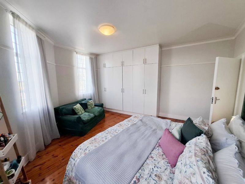 A well-maintained bedroom featuring polished hardwood flooring, ample built-in cupboard storage, and classic picture rail detailing.