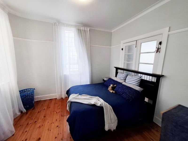 A well-maintained bedroom featuring polished timber flooring, classic picture rails, and charming french doors that provide natural light.