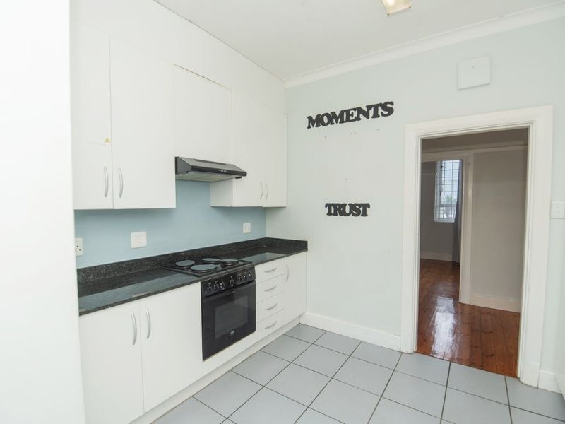 A functional kitchen featuring white cabinetry, granite countertops, and built-in cooking appliances with tiled flooring.
