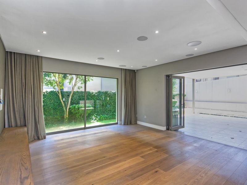 Spacious living area featuring hardwood flooring, recessed lighting, built-in speakers, and seamless indoor-outdoor flow through large sliding and folding doors to the patio.