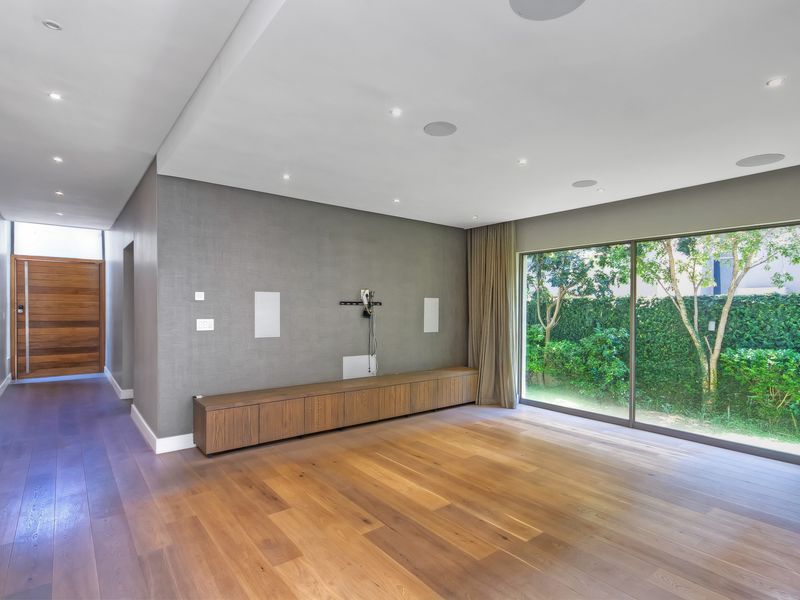 Spacious living area featuring hardwood flooring, built-in cabinetry, recessed lighting, and large sliding glass doors providing access to the garden.