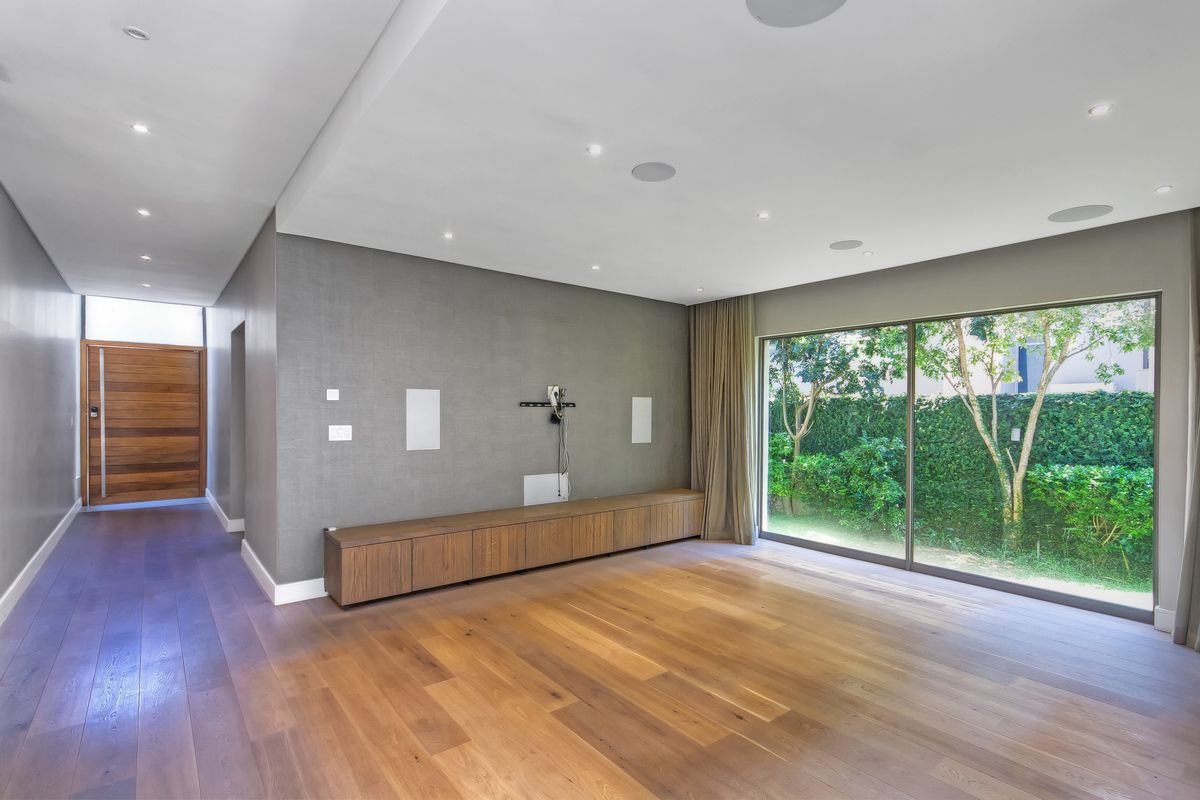 Spacious living area featuring hardwood flooring, built-in cabinetry, recessed lighting, and large sliding glass doors providing access to the garden.