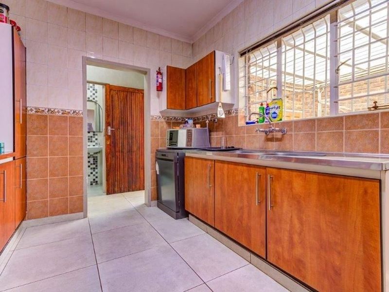 Functional kitchen featuring laminate cabinetry, tiled backsplash, stainless steel sink, and tiled flooring with a window providing natural light.