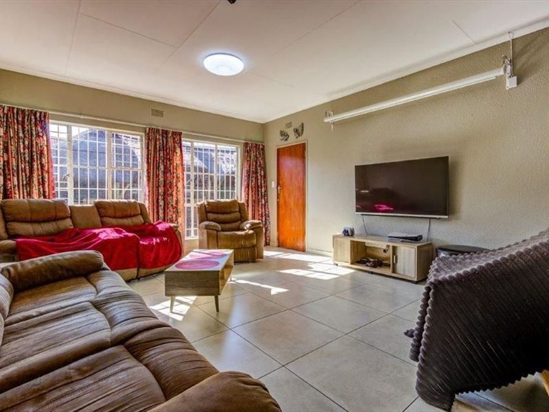 A spacious living room featuring large windows, tiled flooring, and a neutral wall finish, providing a comfortable and functional area for relaxation.