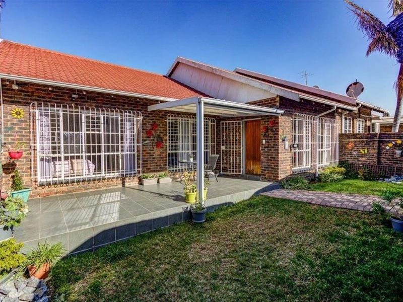 Rear view of the townhouse featuring a brick facade, a covered patio area, and a private garden with a paved walkway.