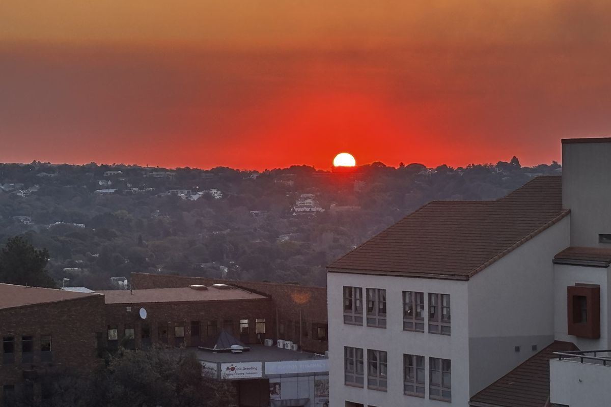 A scenic elevated view of the surrounding neighbourhood and horizon during a vibrant sunset.