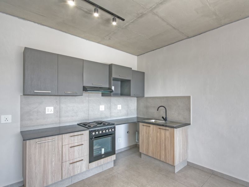 Modern kitchen featuring two-tone cabinetry, stone countertops, built-in oven with gas hob, and an industrial-style exposed concrete ceiling.