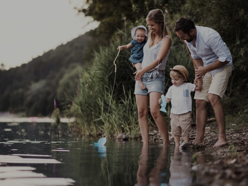 A family standing by a lake shore, showing natural landscape and water frontage.