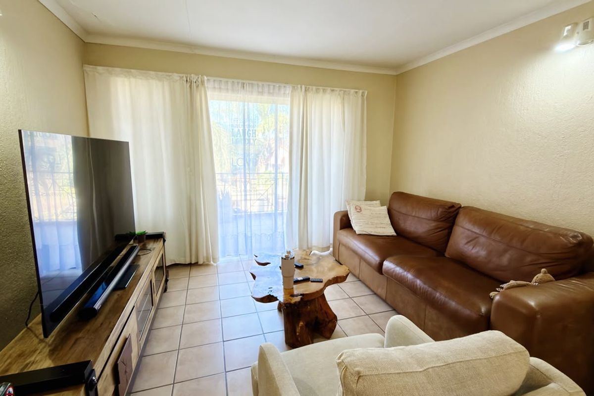 A comfortable living room featuring tiled flooring and a sliding glass door that provides access to an outdoor balcony area.
