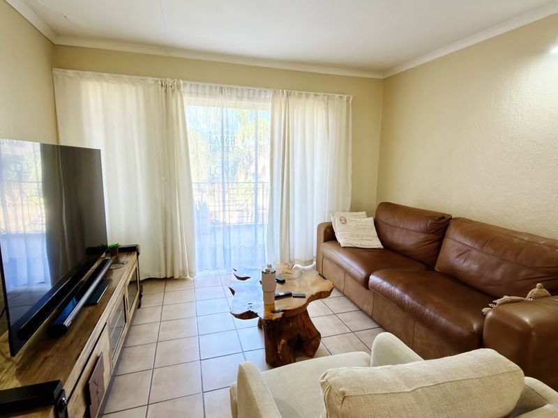 A comfortable living room featuring tiled flooring and a sliding glass door that provides access to an outdoor balcony area.