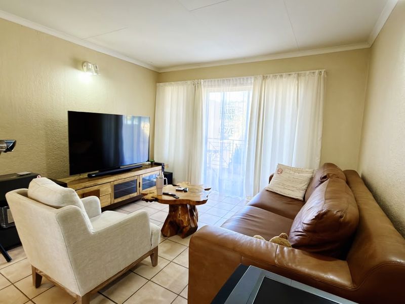 A comfortable living room featuring tiled flooring, coved ceilings, and a sliding glass door providing access to an outdoor area.