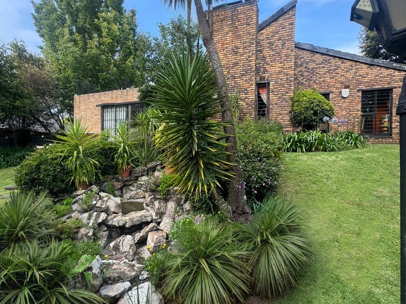 Front view of a brick-faced house featuring a landscaped garden with a rockery and established greenery.