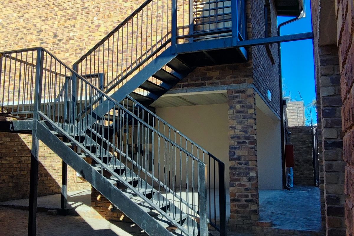 Rear exterior view of the apartment building featuring a durable brick facade and an external metal staircase leading to an upper level.