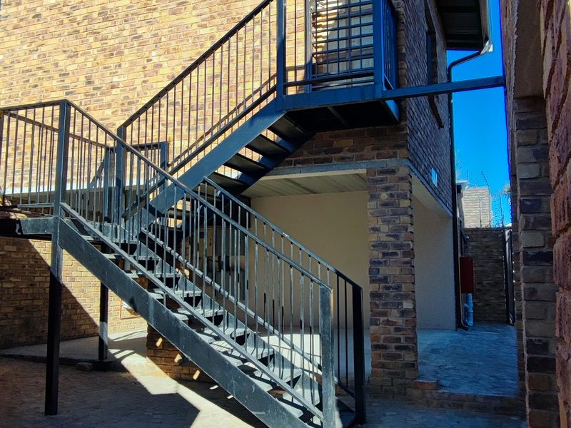Rear exterior view of the apartment building featuring a durable brick facade and an external metal staircase leading to an upper level.