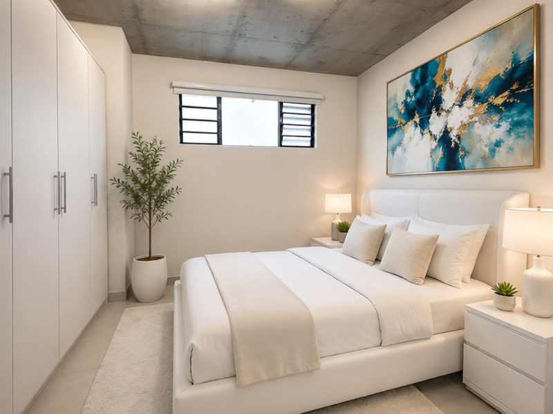 Modern bedroom featuring an exposed concrete ceiling, built-in floor-to-ceiling wardrobes, tiled flooring, and a high-level louvre window for natural light.