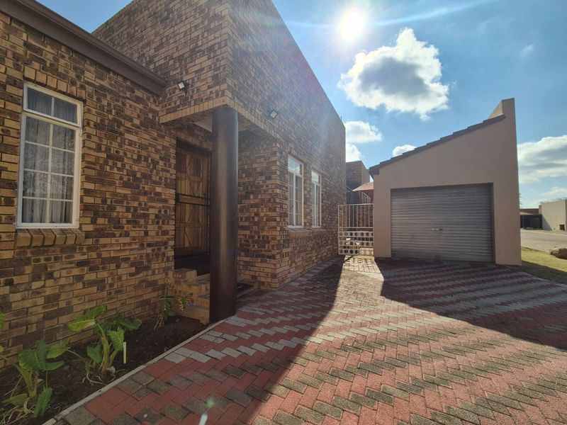 Front exterior view of a face brick townhouse featuring a paved driveway, single garage, and secure entrance.