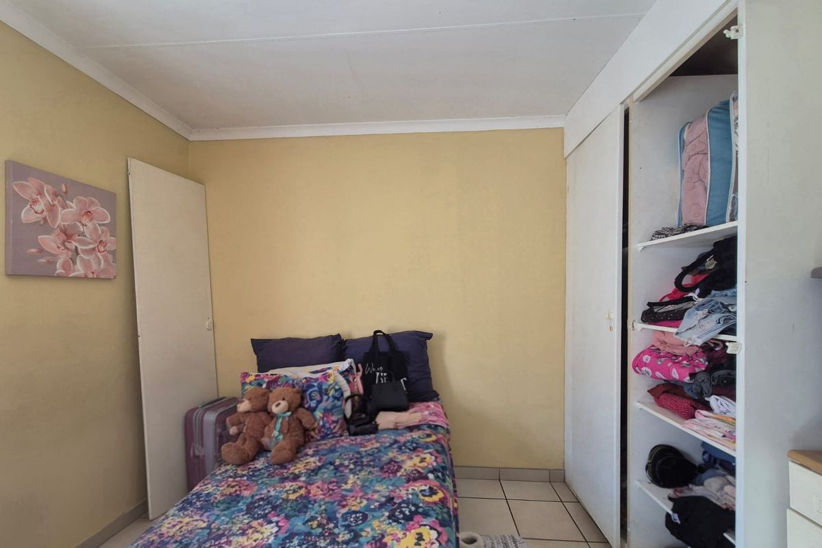 A bedroom featuring tiled flooring and a built-in wardrobe with open shelving.