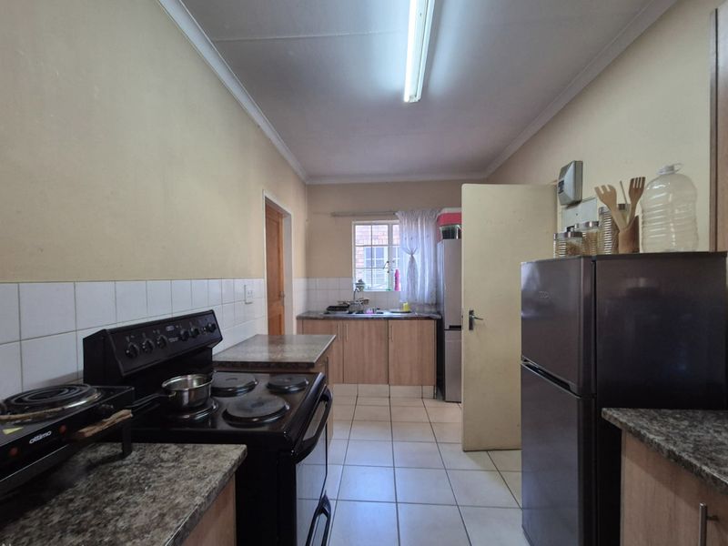 A functional galley-style kitchen featuring tiled flooring, laminate countertops, a tiled splashback, and built-in cabinetry with a freestanding stove.