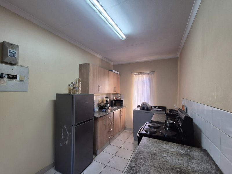 A functional kitchen featuring built-in cabinetry, granite countertops, tiled flooring, and an electric stove, offering a practical layout for daily meal preparation.