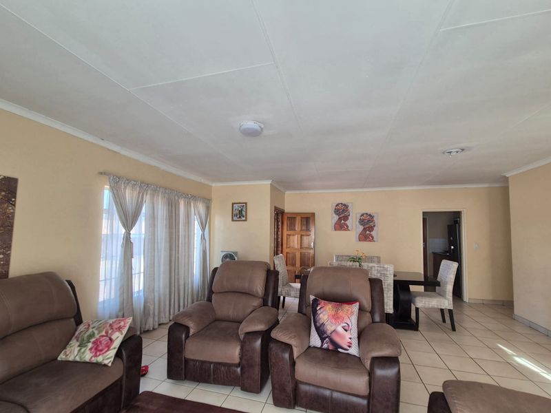 Spacious open-plan living and dining area featuring neutral wall tones, tiled flooring, and direct access to adjacent rooms.