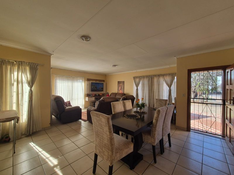 Spacious open-plan living and dining area featuring tiled flooring and direct access to the exterior through a security gate.