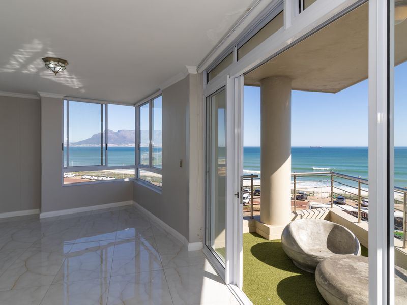 Bright, open-plan living area featuring polished tile floors, expansive windows, and direct access to a balcony with stunning ocean and mountain views.