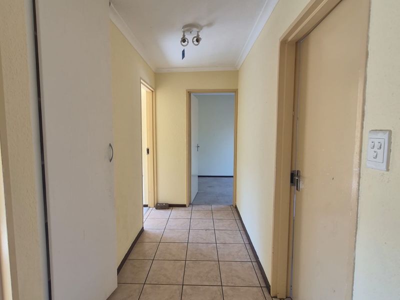 A functional hallway featuring tiled flooring, built-in storage cupboards, and access to multiple rooms within the townhouse.