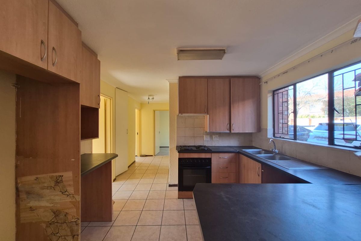 A functional kitchen featuring laminate cabinetry, built-in oven, gas hob, and double basin sink, with tiled flooring and ample counter space.