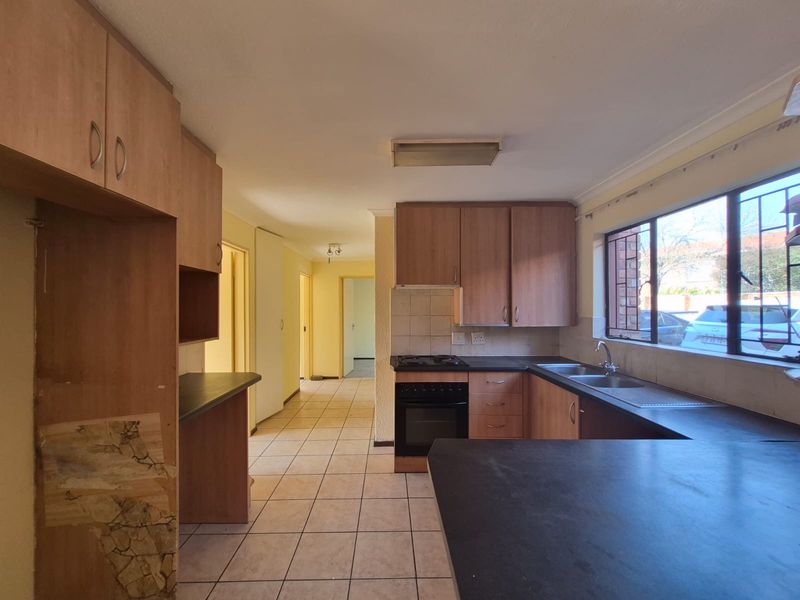 A functional kitchen featuring laminate cabinetry, built-in oven, gas hob, and double basin sink, with tiled flooring and ample counter space.