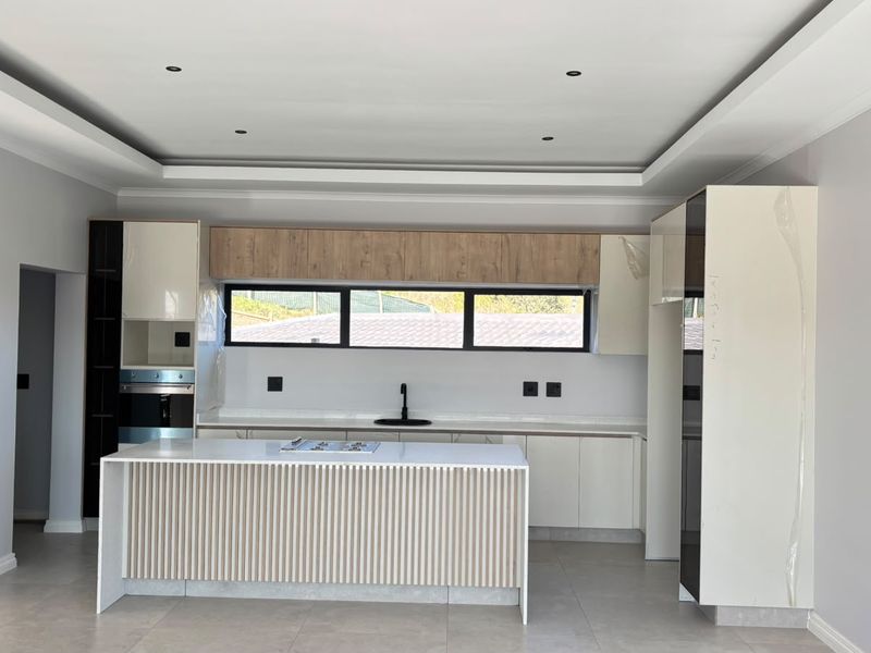 Modern kitchen featuring a central island with hob, sleek built-in cabinetry, integrated oven, and contemporary finishes in a bright, open-plan space.