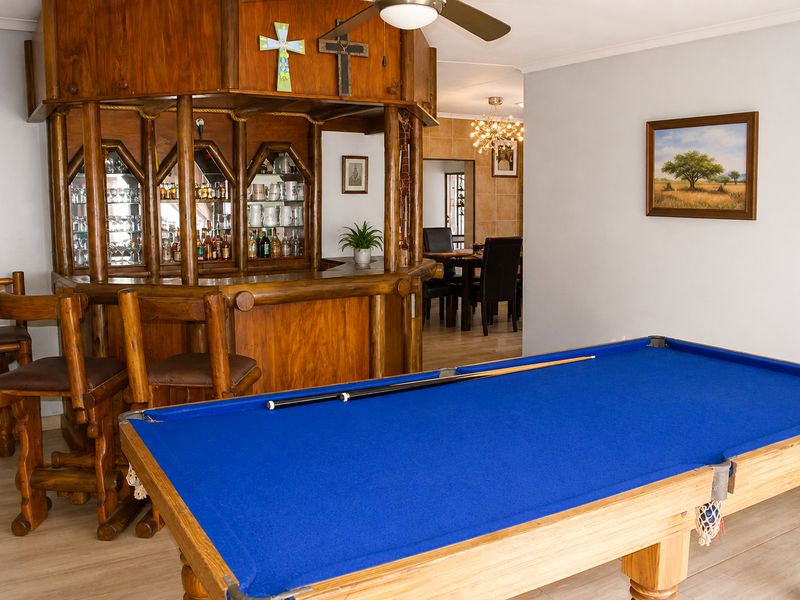 A dedicated entertainment area featuring a built-in wooden bar counter, ceiling fan, and laminate flooring, with an adjacent dining space visible.