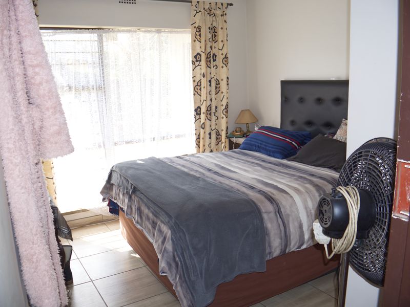 A functional bedroom featuring tiled flooring and a large window allowing for natural light.