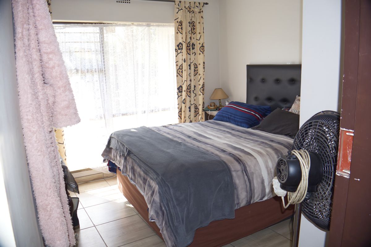 A functional bedroom featuring tiled flooring and a large window allowing for natural light.