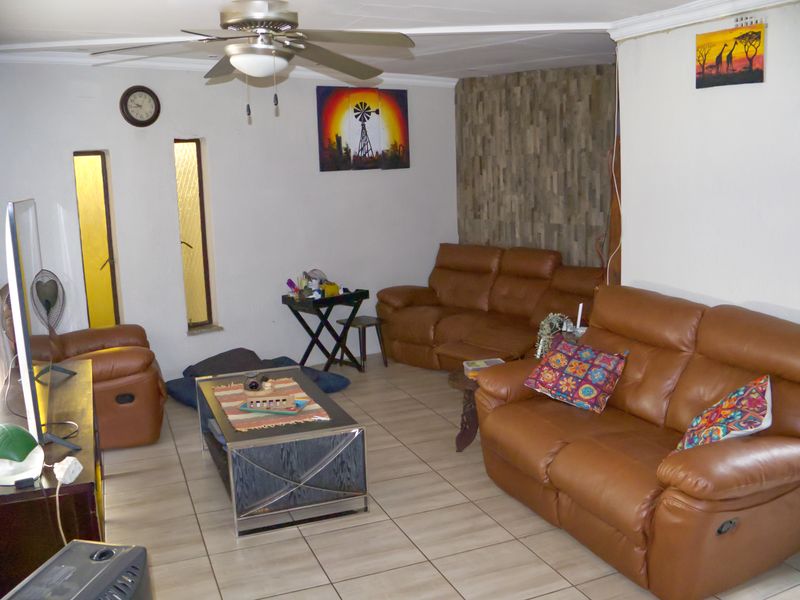 A living room featuring tiled flooring, a ceiling fan, and a textured feature wall, providing a functional and comfortable living space.