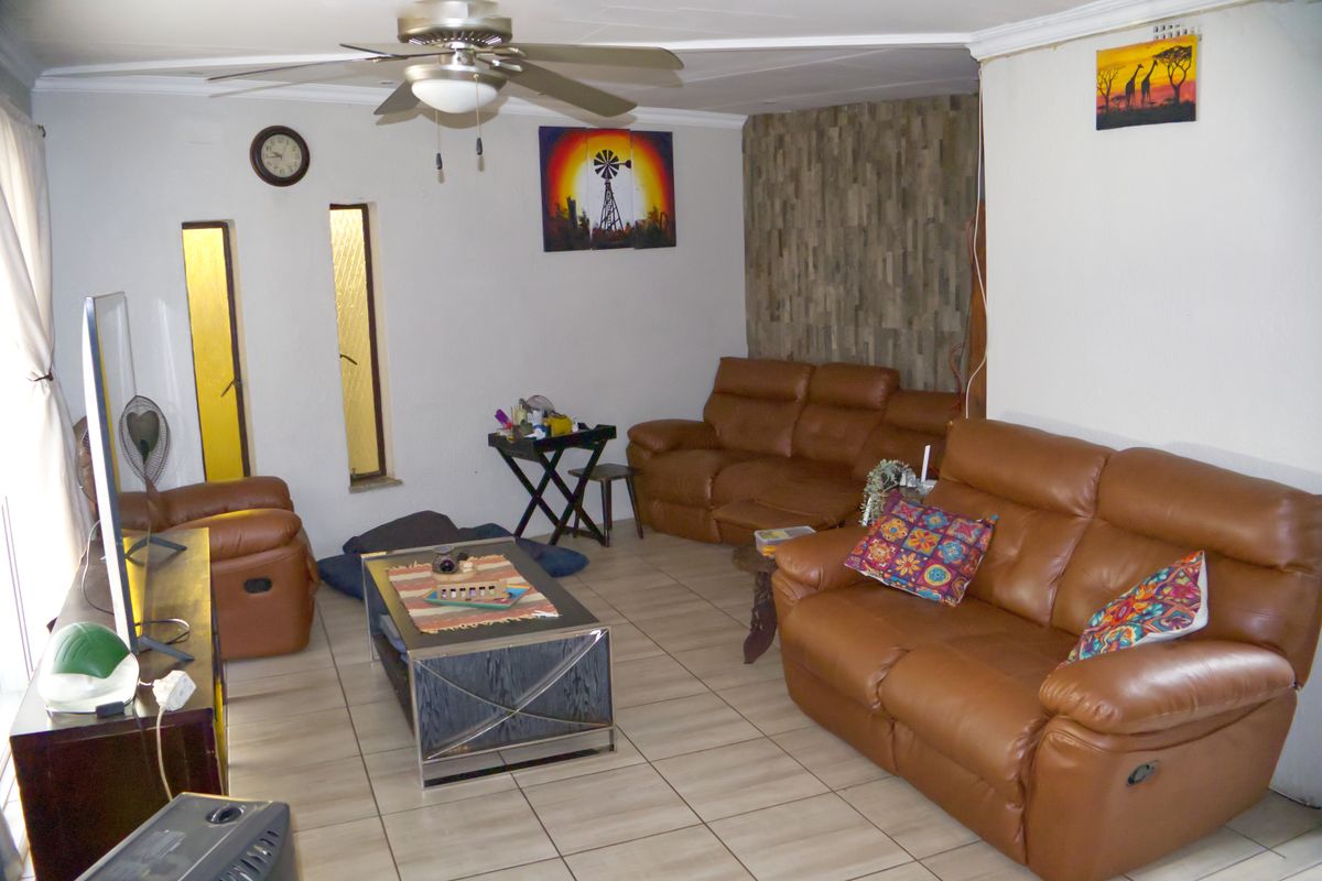 A living room featuring tiled flooring, a ceiling fan, and a textured feature wall, providing a functional and comfortable living space.