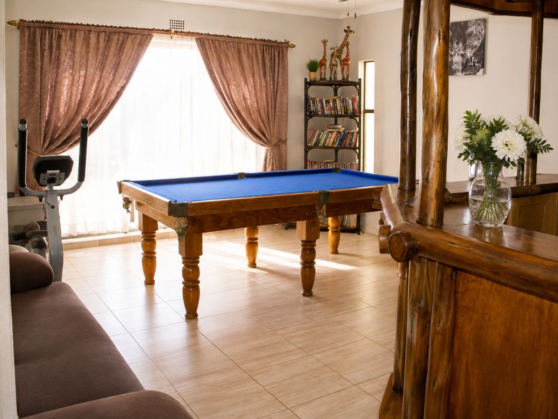 A dedicated bar area featuring a rustic wooden bar counter and tiled flooring, currently utilized as a recreational space with a pool table.