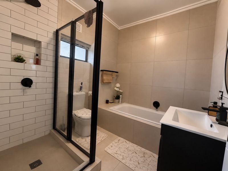 Modern bathroom featuring a glass-enclosed shower, built-in bathtub, contemporary vanity, and stylish subway tile accents.