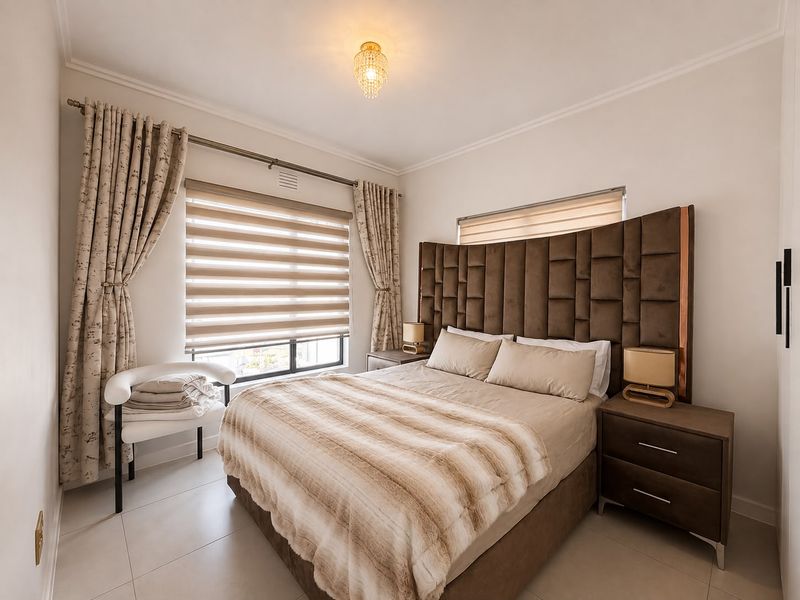 A well-maintained bedroom featuring tiled flooring, a large integrated headboard, and dual-layer roller blinds for adjustable natural light.
