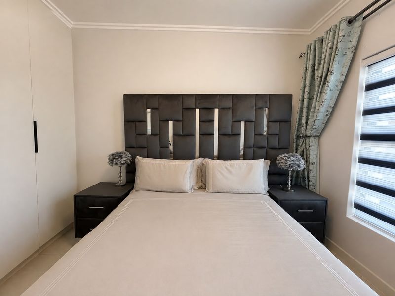 A well-maintained bedroom featuring a built-in wardrobe, modern roller blinds, and neutral finishes, providing a clean and comfortable living space.