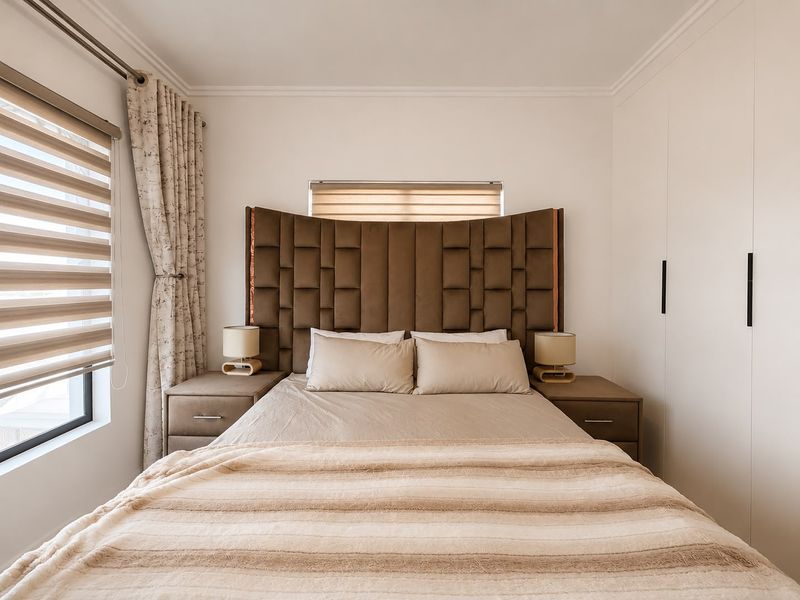 A well-maintained bedroom featuring built-in cupboards, neutral finishes, and modern window treatments, providing a clean and functional living space.