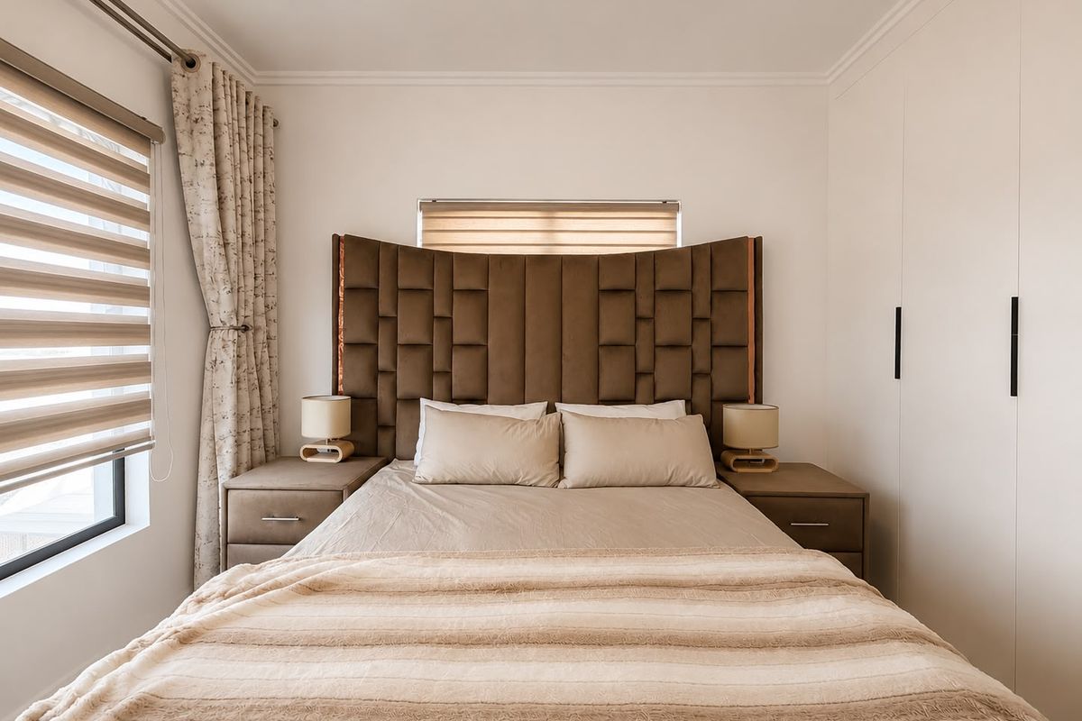 A well-maintained bedroom featuring built-in cupboards, neutral finishes, and modern window treatments, providing a clean and functional living space.