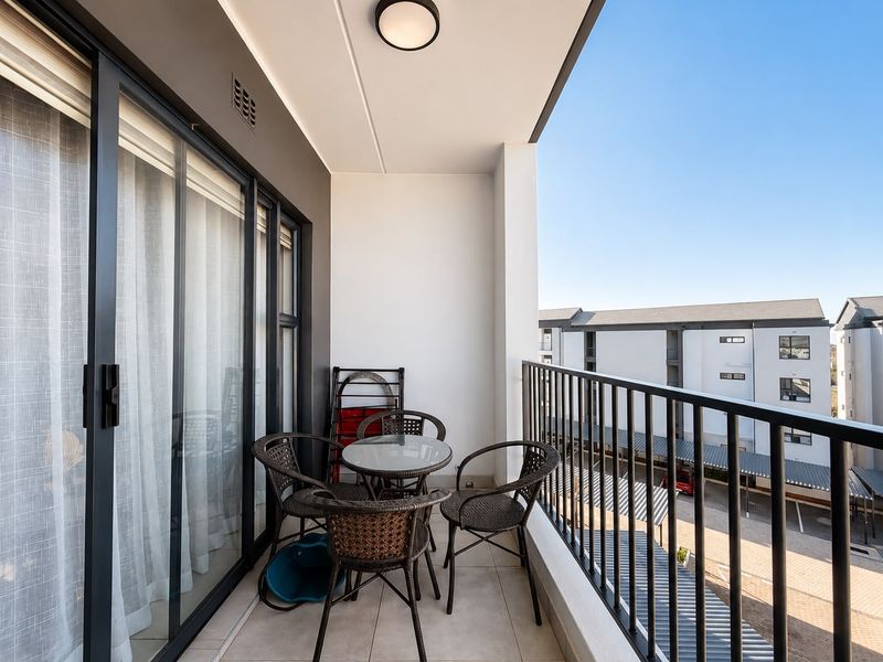 A covered balcony featuring tiled flooring, a metal balustrade, and sliding glass door access to the interior living space.