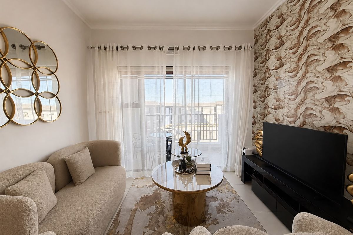 A well-maintained living room featuring a large sliding glass door leading to a balcony, complemented by a decorative textured feature wall.
