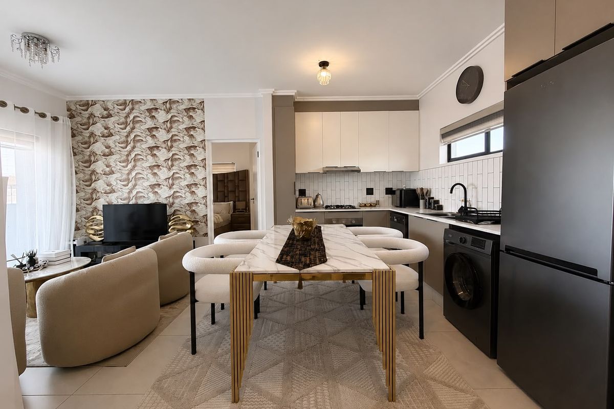 Modern open-plan living and kitchen area featuring sleek cabinetry, subway tile backsplash, integrated appliances, and tiled flooring in a well-maintained apartment setting.