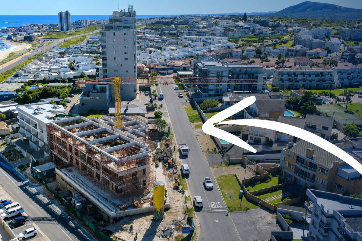 Aerial view of a coastal neighborhood showing a construction site and surrounding residential apartment buildings.