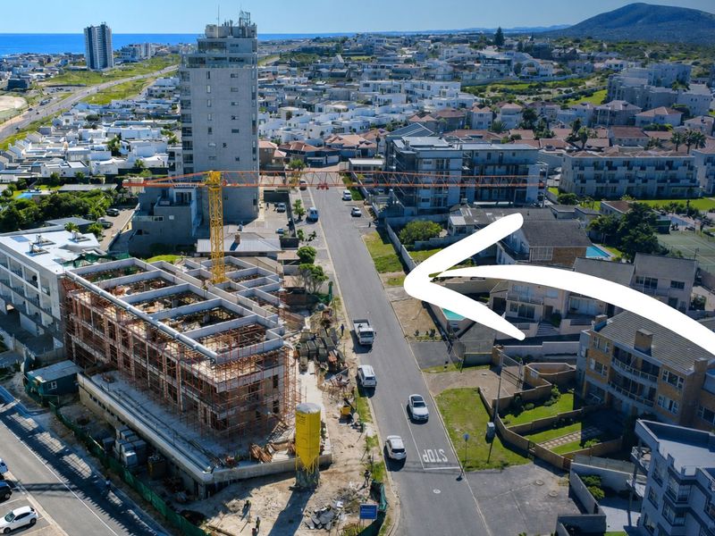 Aerial view of a coastal neighborhood showing a construction site and surrounding residential apartment buildings.