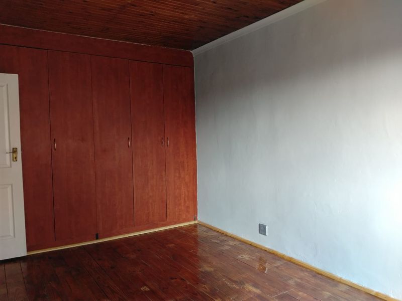 An empty bedroom featuring polished hardwood flooring, a dark wood-paneled ceiling, and extensive built-in wooden cabinetry.